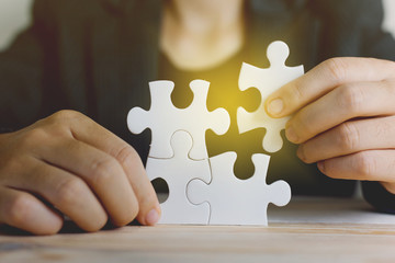 Hands of working woman connecting jigsaw puzzle with light effect, Business solutions, success and...