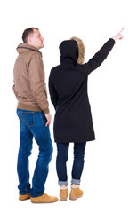 Back view of couple couple in winter jackets pointing.
