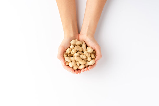 Overhead shot of woman’s hands holding peanuts isolated on white background
