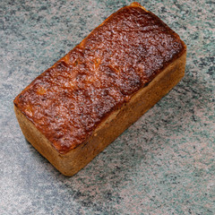 rectangular loaf of wheat bread with a baked shiny crust on the kitchen table.