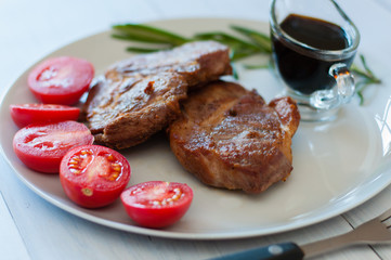 Tasty, juicy, fried meat steaks of pork or beef with sauce, spices and tomato