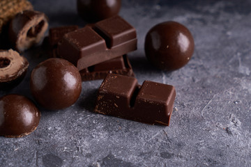 broken black and white chocolate. Pieces of chocolates on a gray stone table