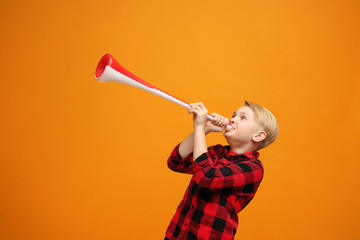  Boy with a big fan trumpet. Beautiful smiling caucasian boy in the red shirt on the yellow...