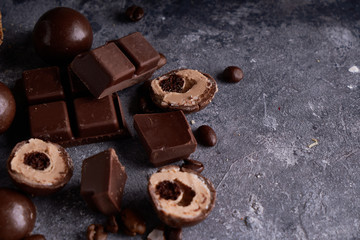 pieces of black and white chocolate, chocolates on a gray stone background Copy space