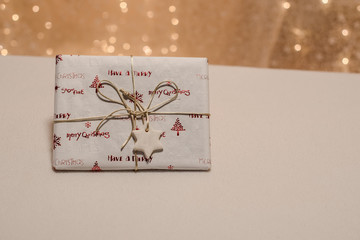 weihnachtsgeschenk mit goldener schleife und geschenkanhaenger stern aus salzteig selbstgemacht ohne aufschrift vor bokeh querformat