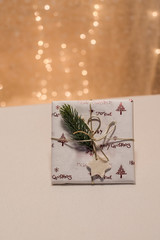 weihnachtsgeschenk mit goldener schleife, tannenzweig und geschenkanhaenger stern aus salzteig selbstgemacht ohne aufschrift vor bokeh hochformat