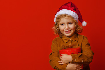 Little curly boy with gift on a red background