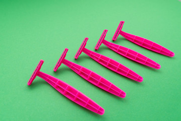 pink female razor on green background