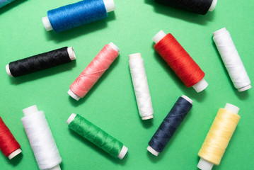colored sewing threads on green background
