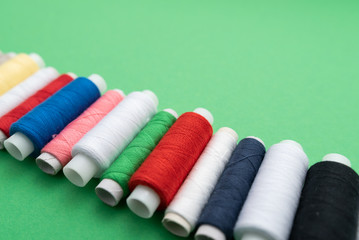 colored sewing threads on green background
