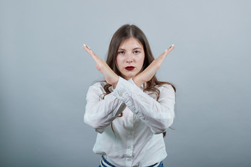 Attractive young woman in fashion white shirt doing stop, NO gesture, looking serious at camera...