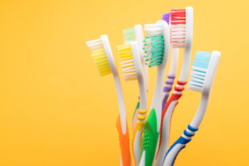 plastic colored toothbrushes on yellow background