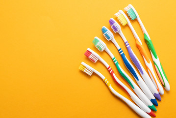 plastic colored toothbrushes on yellow background