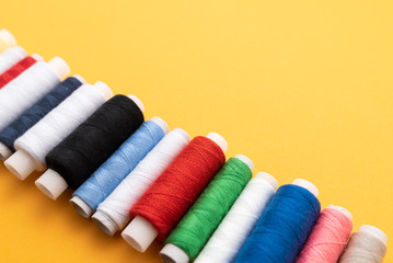 colored sewing threads on yellow background