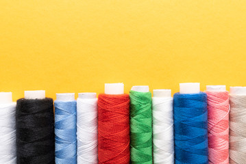 colored sewing threads on yellow background