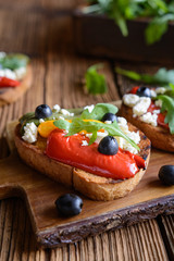 Grilled bread slices topped with baked red, green and yellow bell pepper, black olives, arugula and Feta cheese