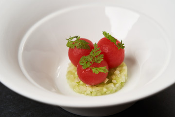 Fresh peeled chili tomatoes and minced cucumbers on dark background