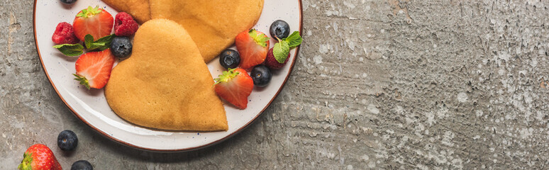 top view of heart shaped pancakes with berries on grey concrete surface, panoramic shot