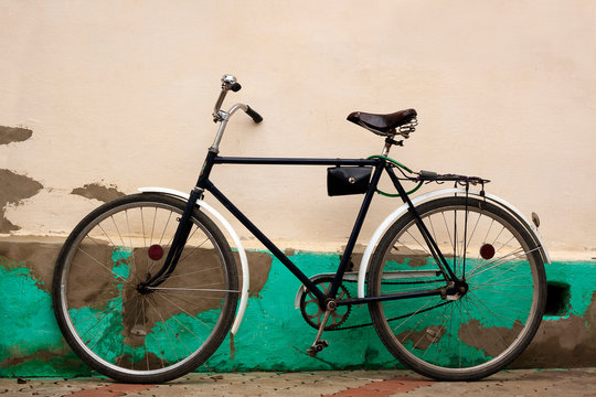 Old fashioned bicycle near rural pale yellow stucco wall