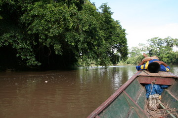Fototapeta na wymiar niño descansando en la proa de una barca por el amazonas