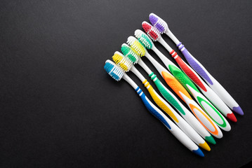 plastic colored toothbrushes on black background