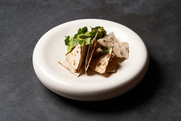 Guacamole with pita chips on white plate. Chef's signature dish