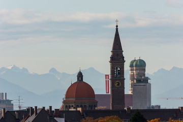 Fototapeta na wymiar Rooftop view of churches in Munich with alpine mountains in the background