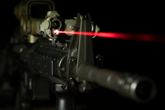 Optical sight and laser device with a red beam on the M4 rifle on dark background