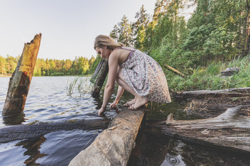 Woman sitting on the shore by the lake washes her hands