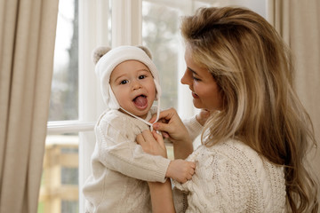 Obraz na płótnie Canvas Mother put a knitted hat on her baby boy