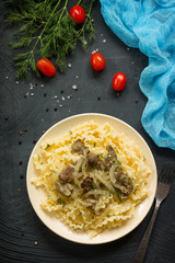 Italian Cuisine. Pasta with meat liver and onion sauce on a stone table. Top view on a flat background lay.
