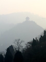 Foggy landscape among mountains with one ancient classical Chinese style of pavilion on the hill.