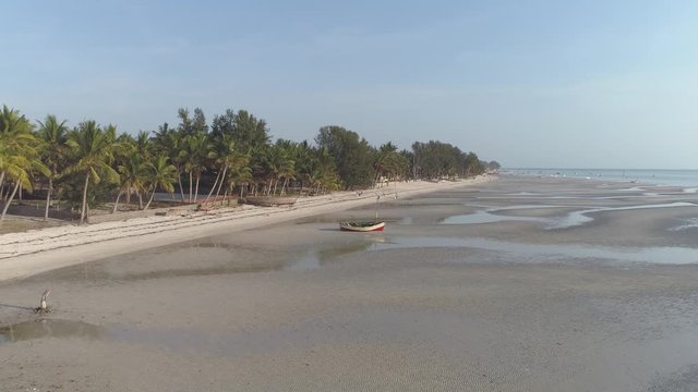 Aerial push in of African tropical beach at low tide with local dhow boats