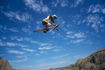 Fototapeta na wymiar Mountain Biker Jumping Against Blue Sky