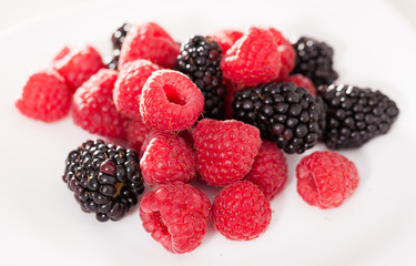 handful of raspberry and blackberry berries on white background