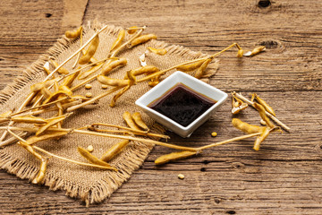 Ripe dry soybeans in pods and dark soy sauce. Cultivated organic agricultural crop, traditional...