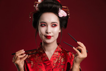 Image of beautiful geisha woman in japanese kimono holding chopsticks