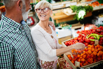 Portrait of beautiful elderly couple in market buing food