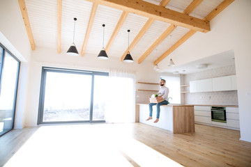 Mature man sitting in unfurnished house, holding a moving box.