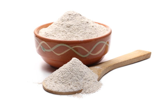 Buckwheat integral flour in clay pot, bowl with wooden spoon isolated on white background 