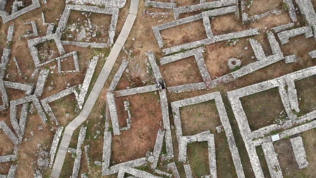 Revealing drone shot of an young caucasian male model lying among ruins of the Shumen fortress in Bulgaria