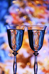 Two glasses with champagne sparkling wine on a festive background with lights and bokeh. Atmosphere of celebration, magic and happiness.