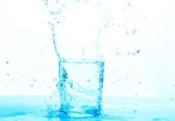 Naklejka na ściany i meble water splashing into a empty water glass, where the pured water is making splash, drops and shapes