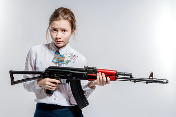 The girl is holding a machine gun on a white background in the studio.