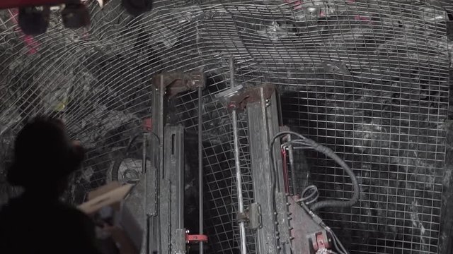 Person operating jumbo underground to drill mesh into rock