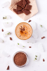 Lassi is a chocolate cold drink next to cocoa, chocolate and ice.