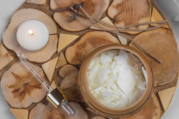 Tools for making candles of white soy wax flakes, essential oil, wicks on wooden background. Flat lay, overhead shot. Ecological lifestyle