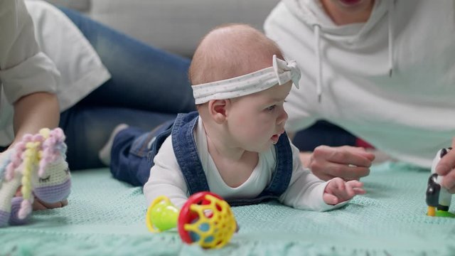 Little girl kid plays a rattle on the floor with parents