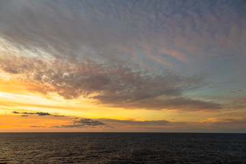 Sunset and dramatic set of clouds drifting over the tropical waters of the Caribbean Sea are lit by the last moments of daylight