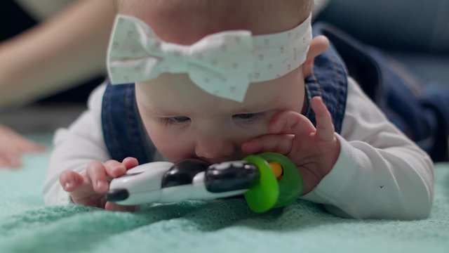Little girl kid plays a rattle on the floor with parents
